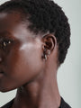 14K solid gold hoop earring with cubic zirconia on a woman's ear.
