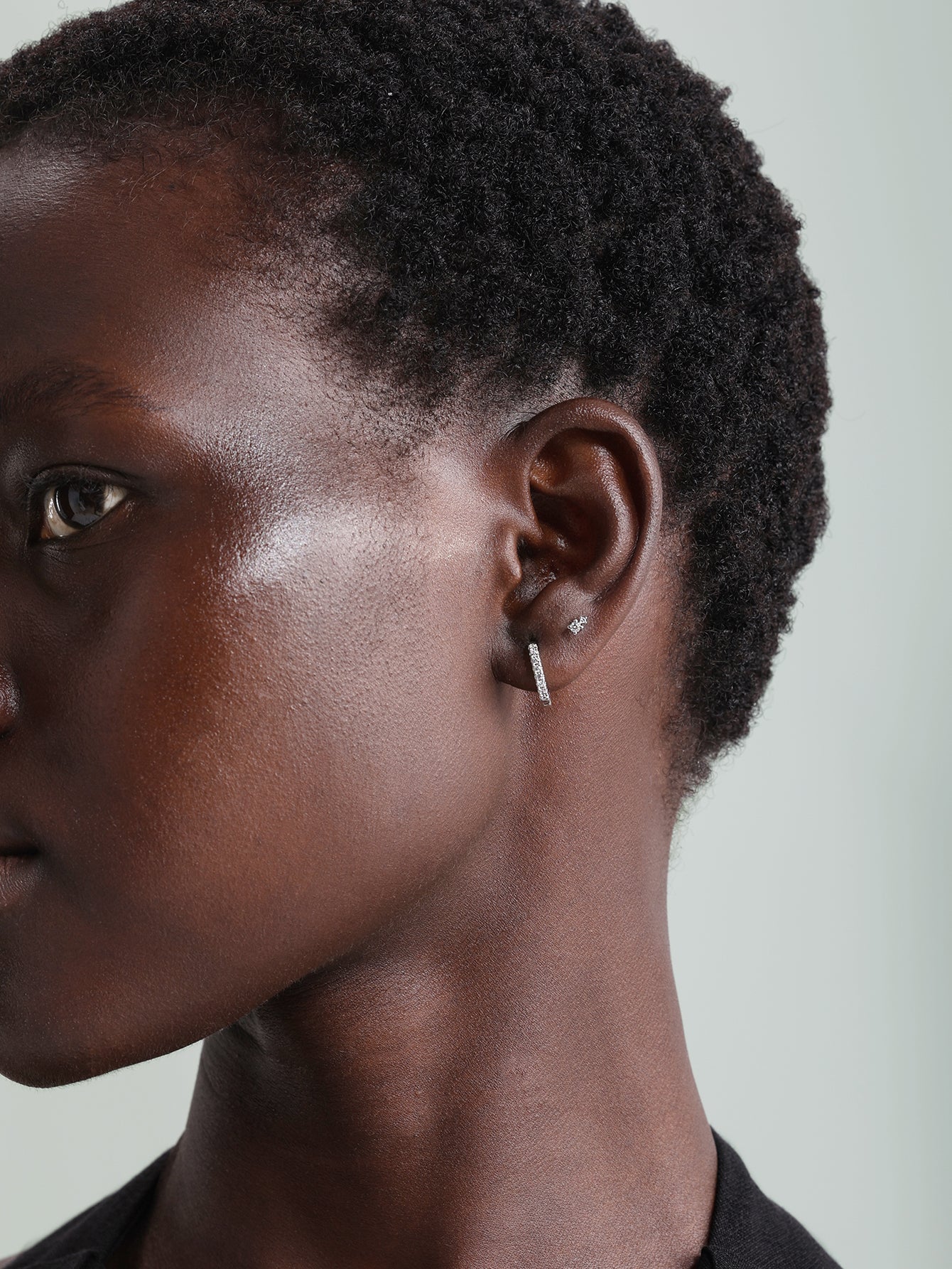 14K solid gold hoop earring with cubic zirconia on a woman's ear.