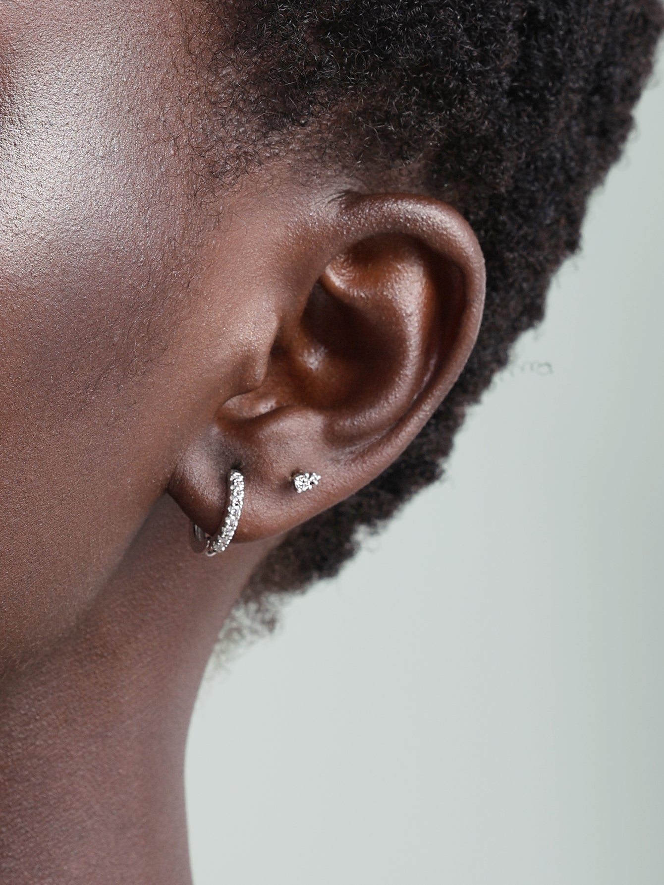 14K solid gold hoop earring with channel-set cubic zirconia worn on ear alongside a small cubic zirconia stud.