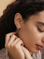 14K solid gold shiny cubic zirconia hoop earring on woman's ear, styled with a star stud and flower drop. Delicate jewelry.