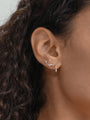 Model wearing a small, glossy 14K solid gold hoop earring with cubic zirconia studs on ear.