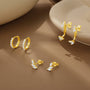 Set of four Kosiner 18k gold-plated copper earring styles: CZ huggie hoops, horse eye leaf studs, & ear jackets.
