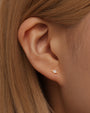 18k gold plated stud earring with quadrilateral cubic zirconia on model's earlobe.