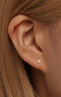18k gold plated stud earring with quadrilateral cubic zirconia on model's earlobe.
