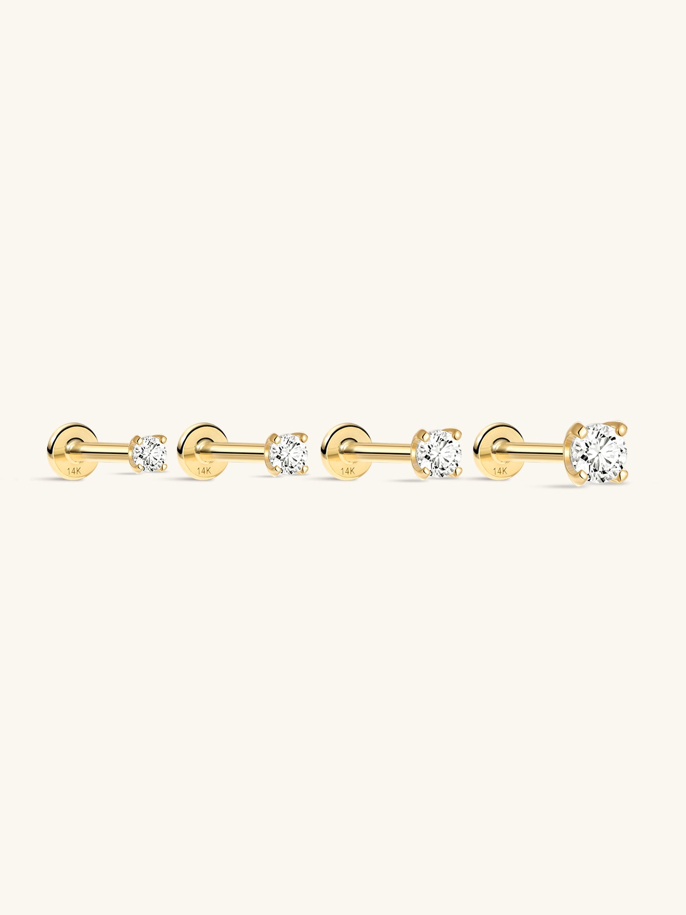 Four 14K solid gold mini stud earrings with cubic zirconia stones and flat back posts, shown in different sizes.