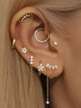 14K gold pave crescent moon stud with 5 clear CZ stones on helix piercing, styled with other earrings.