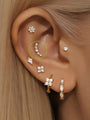 14K gold curved stud earring with five CZ stones on ear, part of a curated ear piercing set.