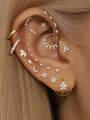 14K solid gold 6mm hoop earring with a flower design made of AAAAA cubic zirconia, shown on ear for scale.