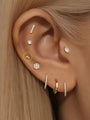 14K gold lightning bolt piercing stud with lab diamond, styled on a woman's ear with other gold jewelry.