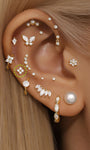 Perno piercing a quattro fiori in oro massiccio 14K con zirconi chiari, modellato sull'orecchio.