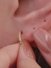 Edgy full ear stacking look with KOSINER Prism 14K solid gold geometric flat back studs, mix of spike dangle studs, chain rook piercing hoop, pave cz helix studs, modern sharp-line cartilage piercing styling for multiple ear placements