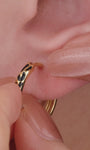 Trendy multi-piercing ear stacking look with KOSINER Puzzle black enamel leopard print sterling silver hoop earring, matched tiny cz studs, geometric triangle studs, textured gold hoops, chic edgy everyday ear styling