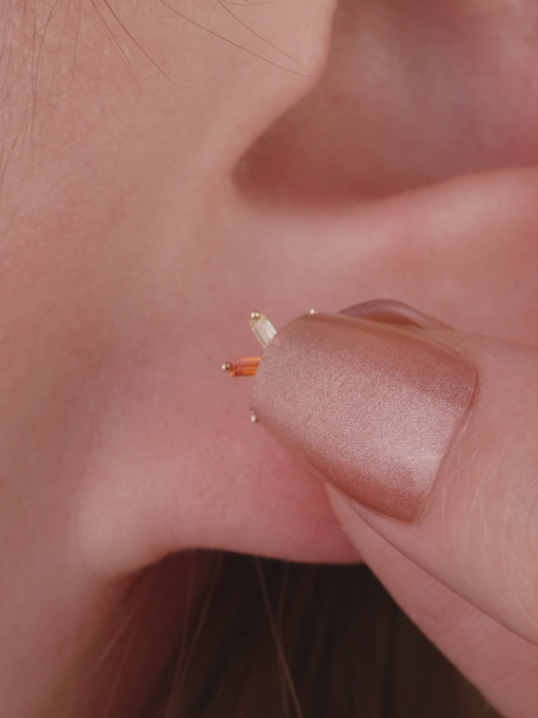 Layered ear stacking look with KOSINER rainbow light series piercing jewelry, featuring colorful baguette flat back studs for multi-position helix, tragus and lobe styling