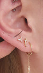 model curated ear stack with 14K gold battle axe drop cartilage stud, layered goth gold piercings closeup lifestyle photo