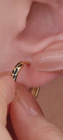 Trendy multi-piercing ear stacking look with KOSINER Puzzle black enamel leopard print sterling silver hoop earring, matched tiny cz studs, geometric triangle studs, textured gold hoops, chic edgy everyday ear styling