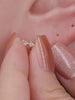Close-up ear shot displaying two sizes of KOSINER Starlight octagonal star flat back studs set on ear lobe piercings, showcasing versatile minimalist wear on deep skin tone
