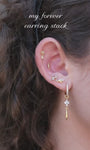 Close-up of KOSINER lotus chain dangle stud styled in a curated ear stack