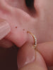 Close-up ear shot showing KOSINER Starlight dainty four-point star flat back stud worn on earlobe, paired with matching star charm hoop, demonstrating minimalist versatile fit on deep skin tone