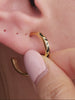 Stylish layered full ear stacking aesthetic with KOSINER Puzzle staggered black white pave cz sterling silver hoop earring, paired tiny cz cartilage studs, geometric two-tone triangle studs, plain polished gold huggie hoop, modern asymmetrical contrast detail everyday ear styling