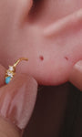 Elegant curated ear stacking look featuring KOSINER Étoile triangular flat back stud on earlobe, matched with sunburst, leaf, square gem studs and gold hoop rings, refined minimalist multi-piercing styling